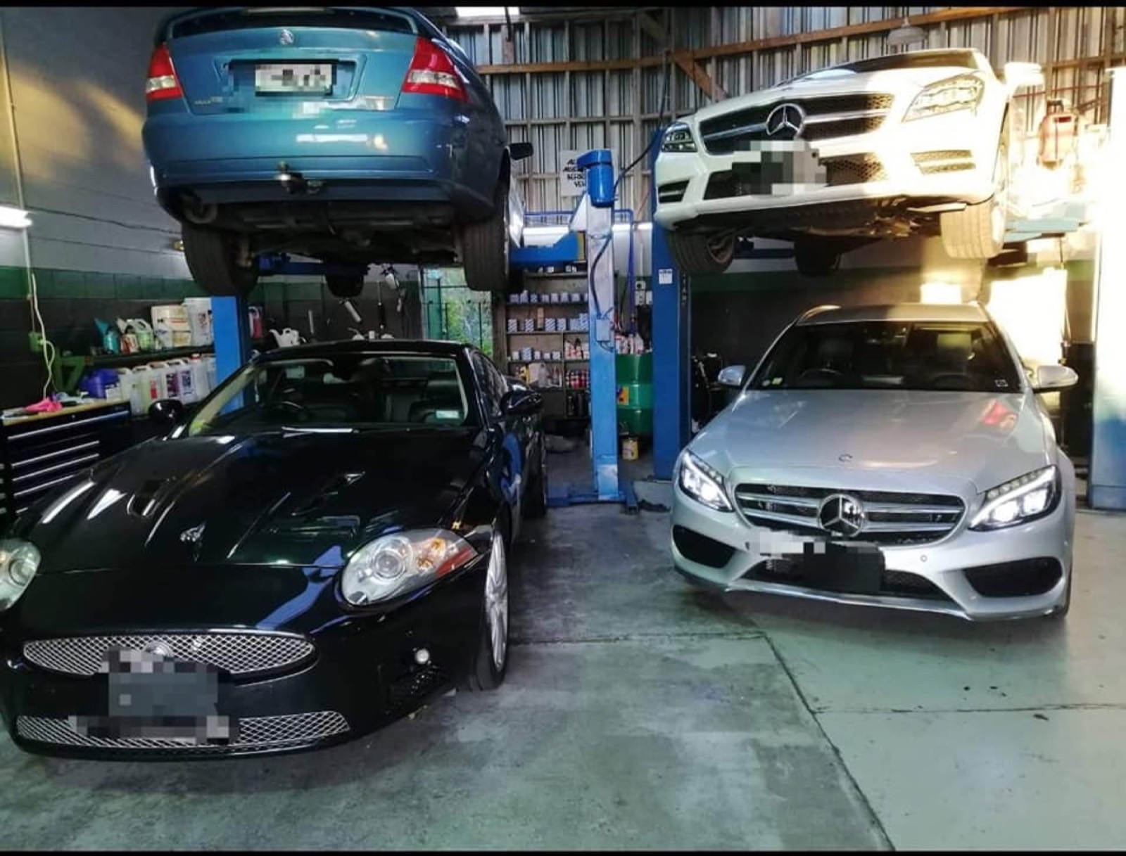 Multiple cars on hoists inside the Precision Automotive workshop
